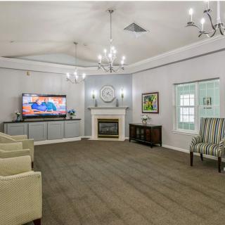 A spacious living room featuring a television, fireplace, elegant chandeliers, and comfortable seating.