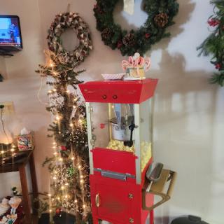 A festive popcorn machine surrounded by holiday decorations, including wreaths and string lights.