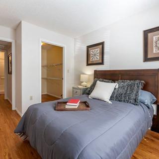 A cozy bedroom with a neatly made bed featuring blue bedding and decorative pillows, complemented by framed artwork on the walls.