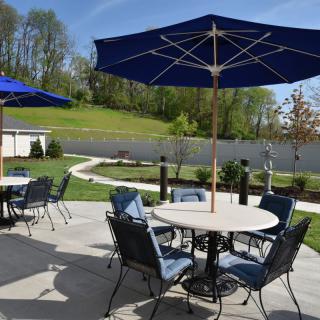 A sunny outdoor patio with tables, chairs, and blue umbrellas.