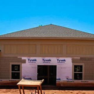 A house under construction with visible siding and roofing.