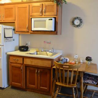 A cozy kitchen setup featuring wooden cabinets, a microwave, and a small dining area.