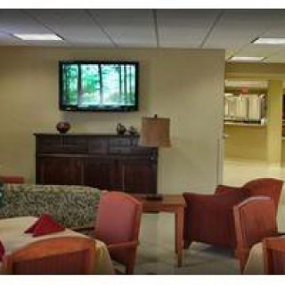 A cozy lobby seating area with comfortable chairs and a television mounted on the wall.
