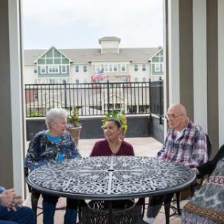 Seniors engage in a lively conversation with their caregiver in a welcoming outdoor space.