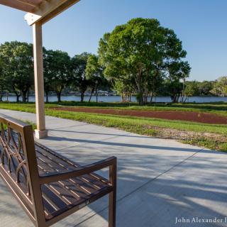 A peaceful park scene with a wooden bench overlooking a lake surrounded by trees.