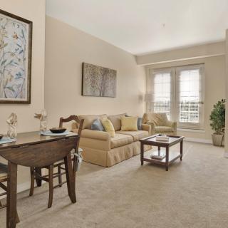 A cozy living room with a dining area, featuring neutral tones and comfortable furniture.