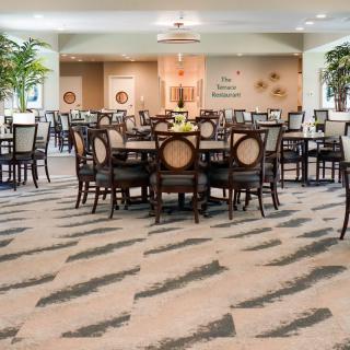 An elegantly arranged dining area with multiple tables and chairs, featuring decorative lighting and indoor plants.