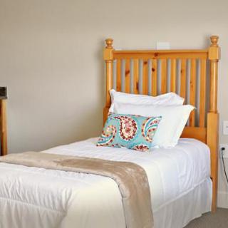 A cozy bedroom featuring a single bed with a wooden headboard, adorned with white bedding and a decorative pillow.