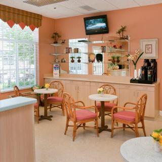 A cozy cafe interior with tables, chairs, a coffee station, and a television.