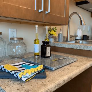 A kitchen countertop with bottles, colorful towels, and glass jars near a sink.