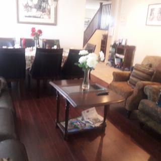 A spacious living and dining area with a hardwood floor, featuring a cozy sofa set and an elegant dining table arrangement.