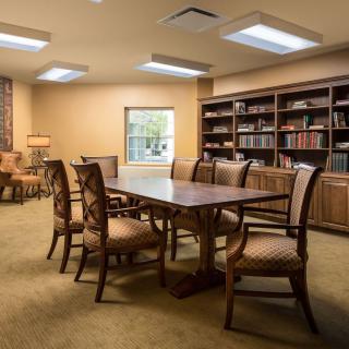 A well-furnished conference room with a large table, surrounded by chairs and bookshelves filled with books.