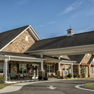 A brick residential building with a covered entrance and manicured landscaping.