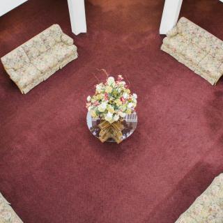 Aerial view of a living room with red carpet, patterned sofas, and a floral centerpiece on a round table.