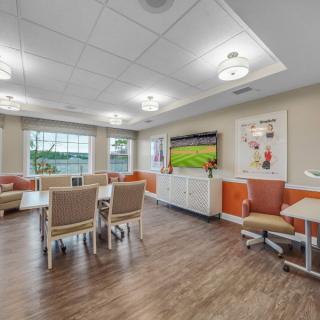 A modern dining area featuring tables and chairs, with a television and artwork on the walls.