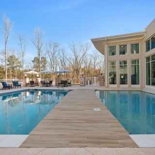 A modern outdoor pool with a wooden deck and surrounding trees.