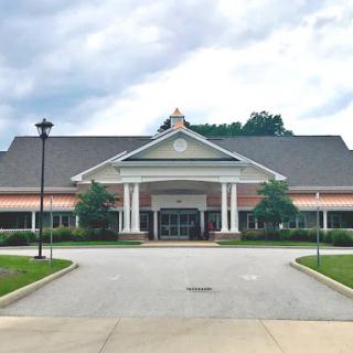 A welcoming entrance to a modern building, set against a cloudy sky.