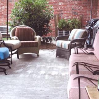 A cozy outdoor patio area with various chairs and a brick wall backdrop.