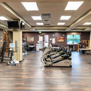A spacious and well-lit gym featuring various exercise equipment.