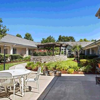 A peaceful courtyard with outdoor seating and a garden under a clear blue sky.