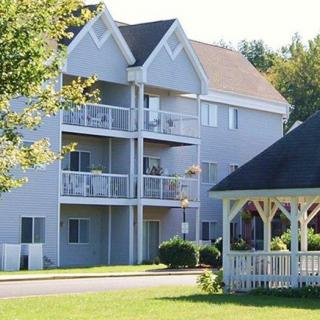 A residential apartment building with balconies and a nearby gazebo surrounded by greenery.