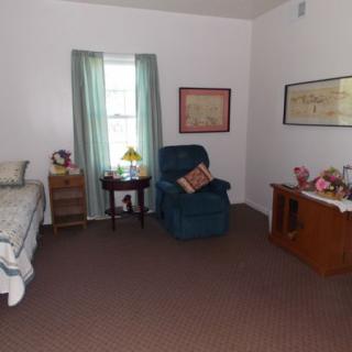 A cozy bedroom featuring a bed, an armchair, side tables, and decorative items.