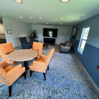 A cozy seating area featuring orange chairs around a circular table, complemented by a television and decorative elements in a modern interior.