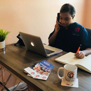 Person working at a desk with a laptop and phone.
