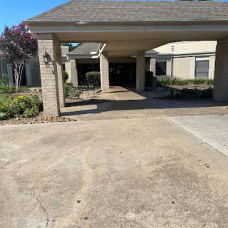 A view of a residential driveway leading to a garage with landscaped areas.