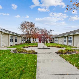 A peaceful courtyard surrounded by buildings with a central tree and neatly maintained lawn.