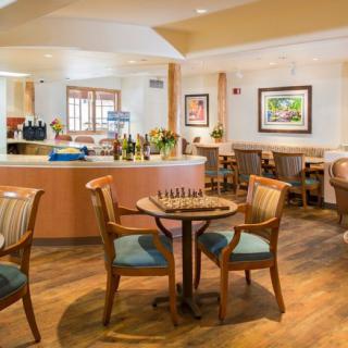 A cozy dining area with wooden tables and chairs, decorated with artwork on the walls.