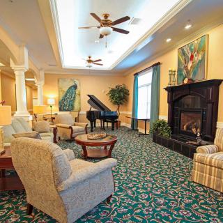 A spacious and elegantly decorated living room featuring a grand piano, fireplace, and comfortable seating.