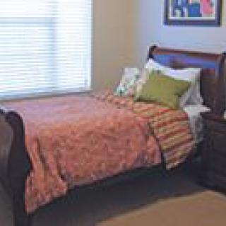 A neatly arranged bedroom with a single bed, nightstand, and window.