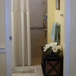 A small bathroom featuring a shower with a curtain, decorated with towels and flowers.