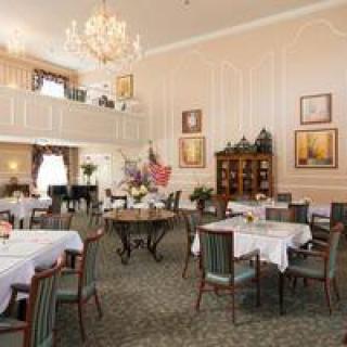 An elegant dining area with neatly arranged tables and chairs, a grand chandelier, and tasteful decorations.