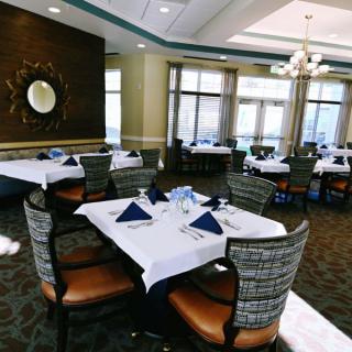An elegant dining area set up with neatly arranged tables and chairs, complete with blue napkin table settings.