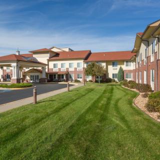 A modern residential building with a well-maintained lawn and clear blue skies.