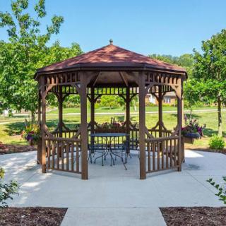 A charming wooden gazebo surrounded by lush greenery, providing a perfect spot for relaxation.