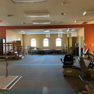 A spacious and well-lit physical therapy room equipped with various exercise tools.