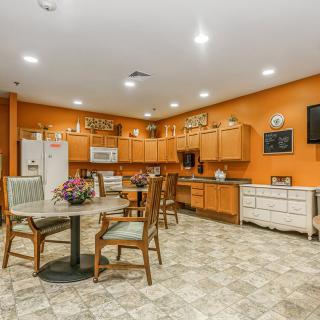 A cozy kitchen and dining area with orange walls, wooden cabinets, and a tile floor.