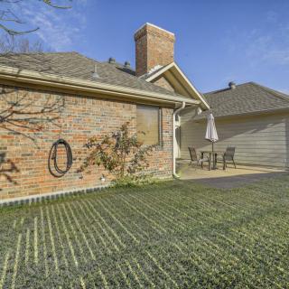 A brick house with a chimney, featuring a backyard patio set under a clear blue sky.