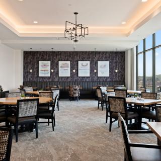 Modern dining area with multiple tables and chairs, featuring large windows and stylish decor.