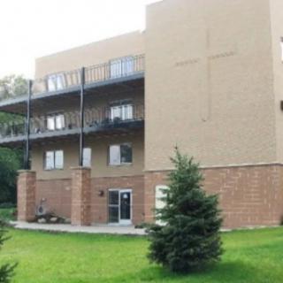 A residential building with balconies and a lawn area in front.
