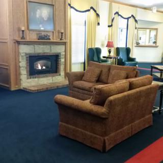 A cozy living room with a fireplace, sofa, and carpeted floor.