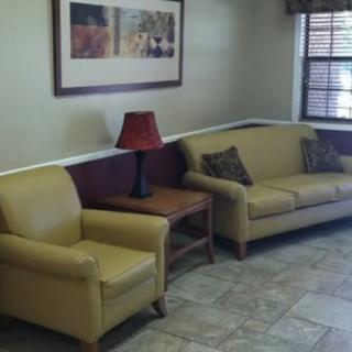 A cozy living room with a sofa, armchair, and a side table topped with a lamp.