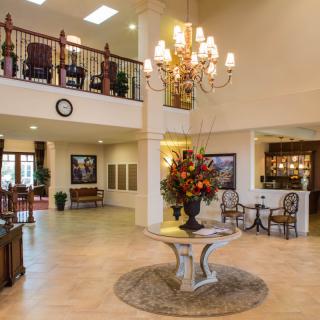 A spacious and elegantly decorated lobby with a chandelier, flowers, and modern furnishings.