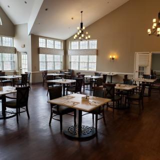 A modern dining area with tables and chairs, featuring large windows and elegant lighting.