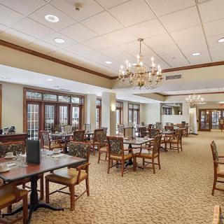 An elegant and spacious dining room with chandeliers and neatly arranged tables and chairs.