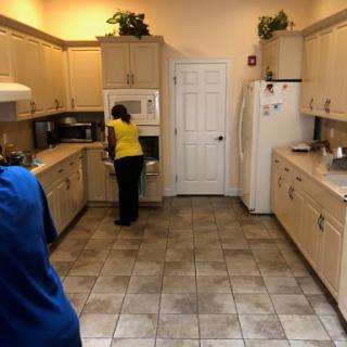 A spacious kitchen with modern appliances and two people engaged in activities.