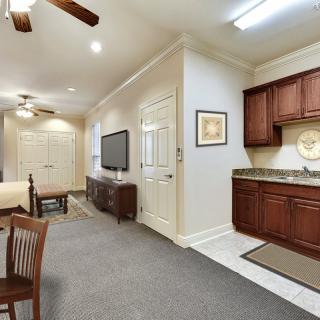A spacious living area with a combined kitchen and dining setup, featuring warm wooden cabinetry and modern amenities.